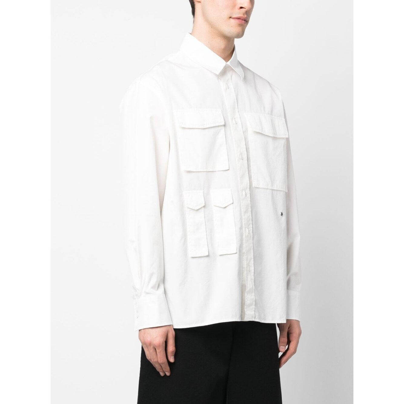 Études white cotton shirt with four pockets, classic collar, long sleeves, and buttoned cuffs, worn by male model. Ideal for casual elegance.