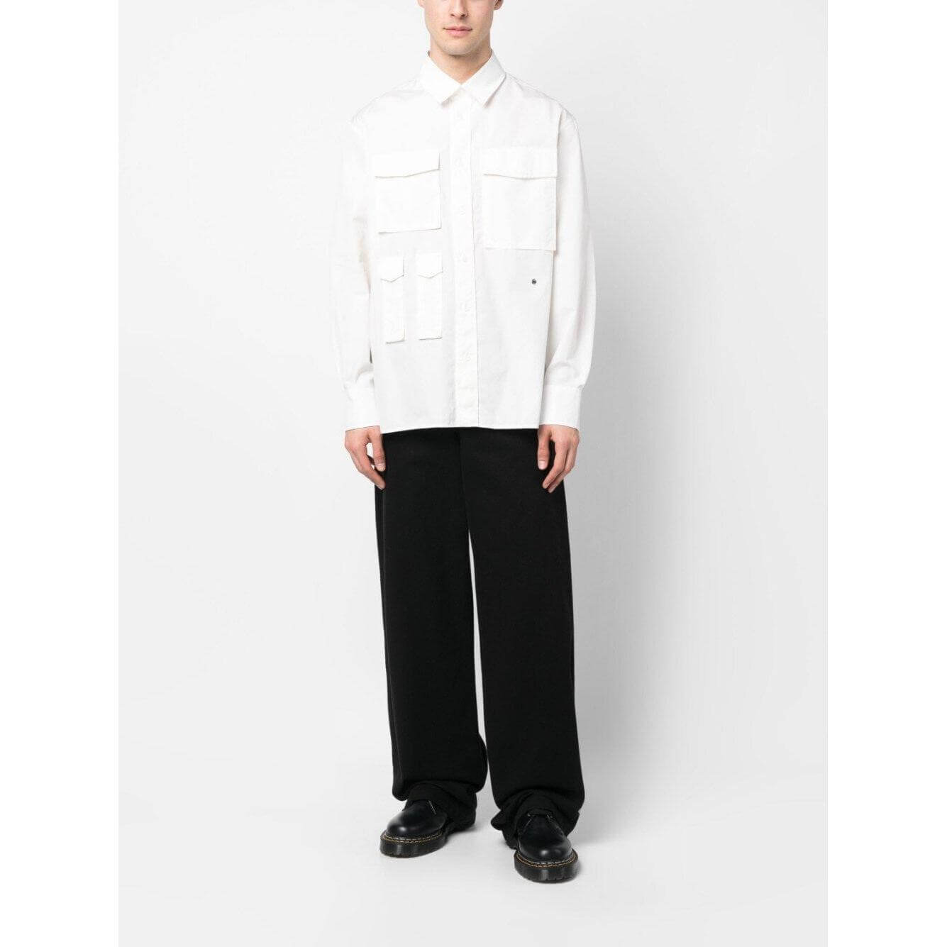 Model wearing Etudes white cotton shirt with four pockets, classic collar, long sleeves, and straight hem, styled with black pants.