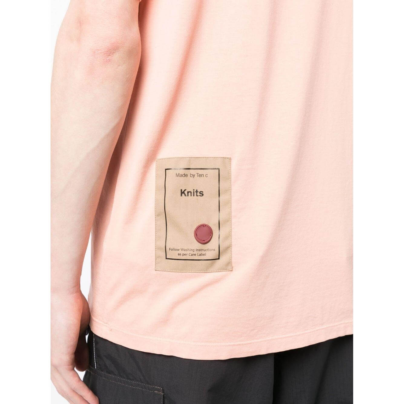 Coral pink TEN C T-shirt back view, featuring a logo patch and round neck design.
