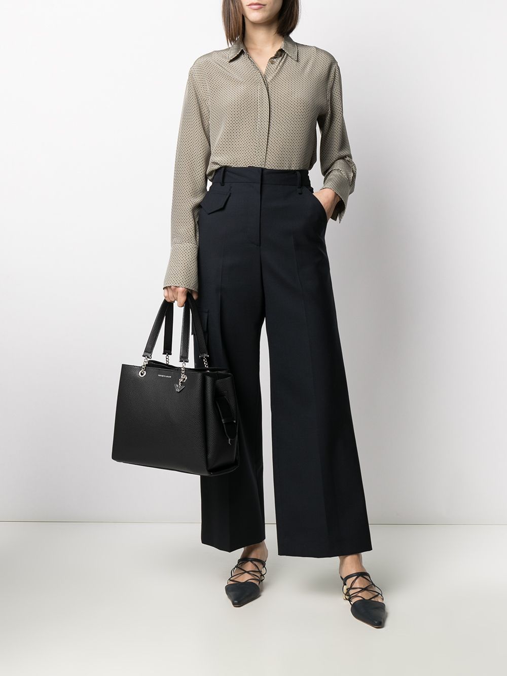 Model holding Emporio Armani black pebbled-effect tote bag with silver-tone logo plaque and shoulder strap.