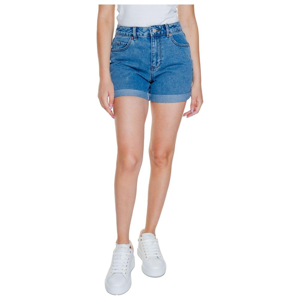 Woman wearing Vero Moda light blue cotton shorts, perfect for spring and summer. High-waisted denim look with white sneakers.