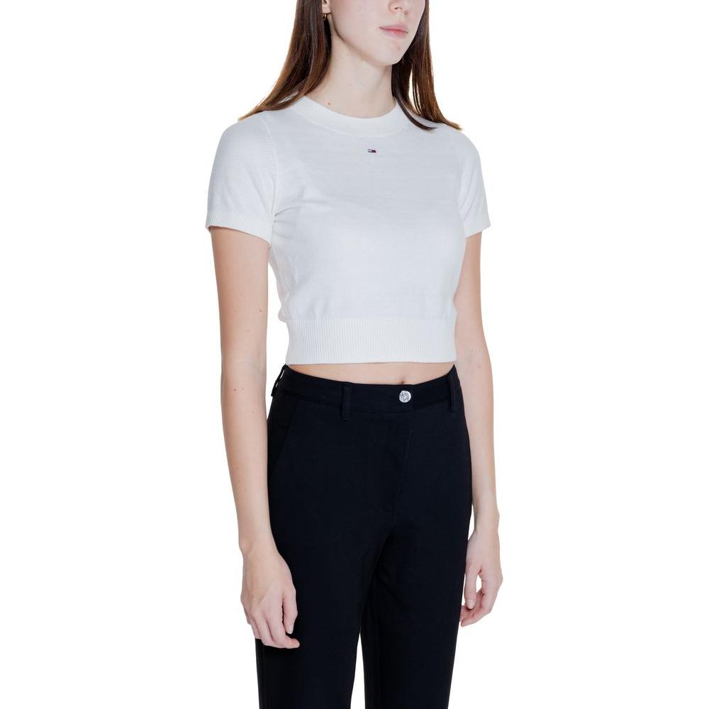 Woman wearing a Tommy Hilfiger white organic cotton short sleeve knit top, part of the Fall/Winter collection, paired with black pants.