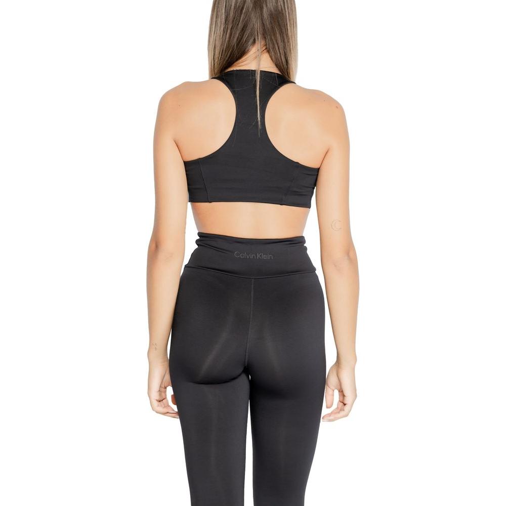 Back view of a woman wearing Calvin Klein black sports bra and leggings, showcasing modern design and fit for active wear.
