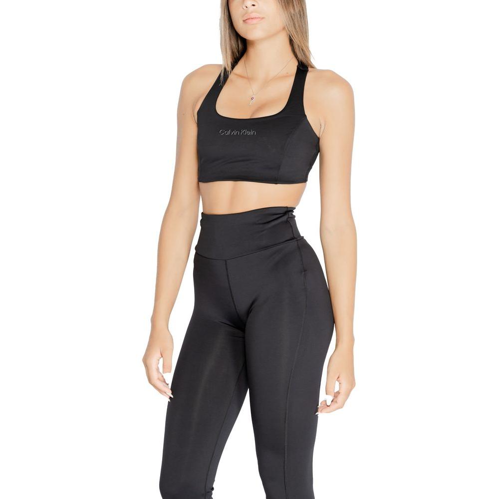 Woman wearing Calvin Klein black sports bra and leggings, polyester blend, showcasing minimalist design and fit for active women.