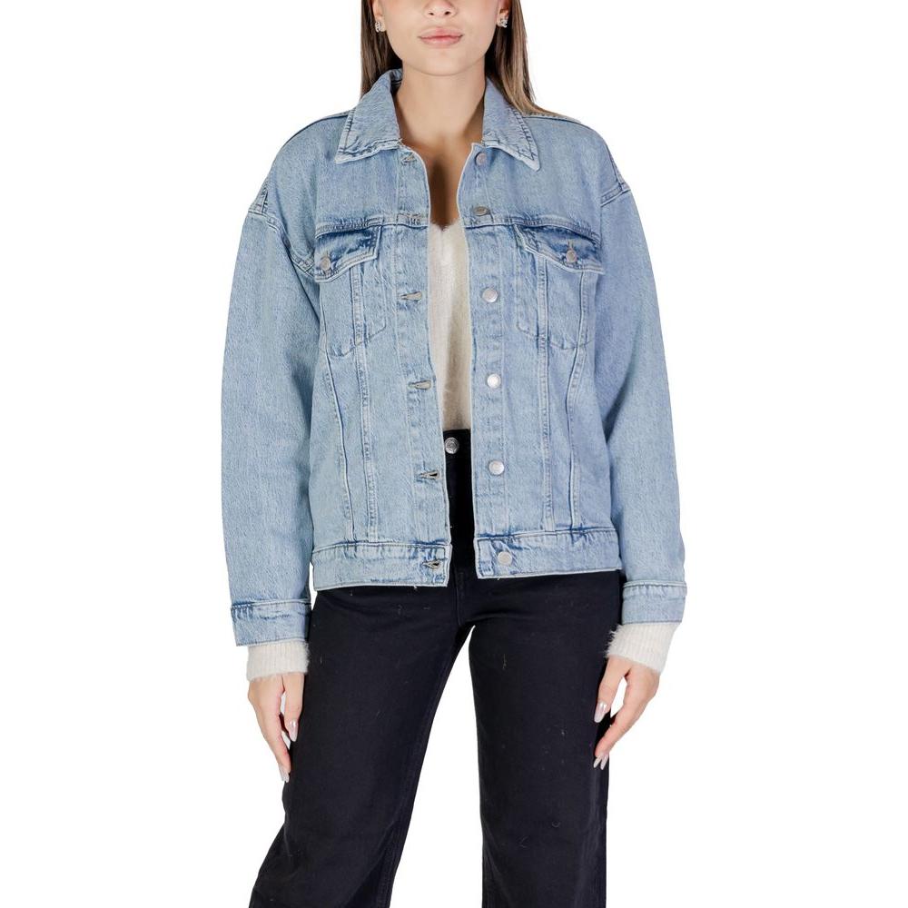 Woman wearing Vero Moda light blue cotton denim jacket, fall/winter collection, with a blend of cotton, polyester, and recycled materials.