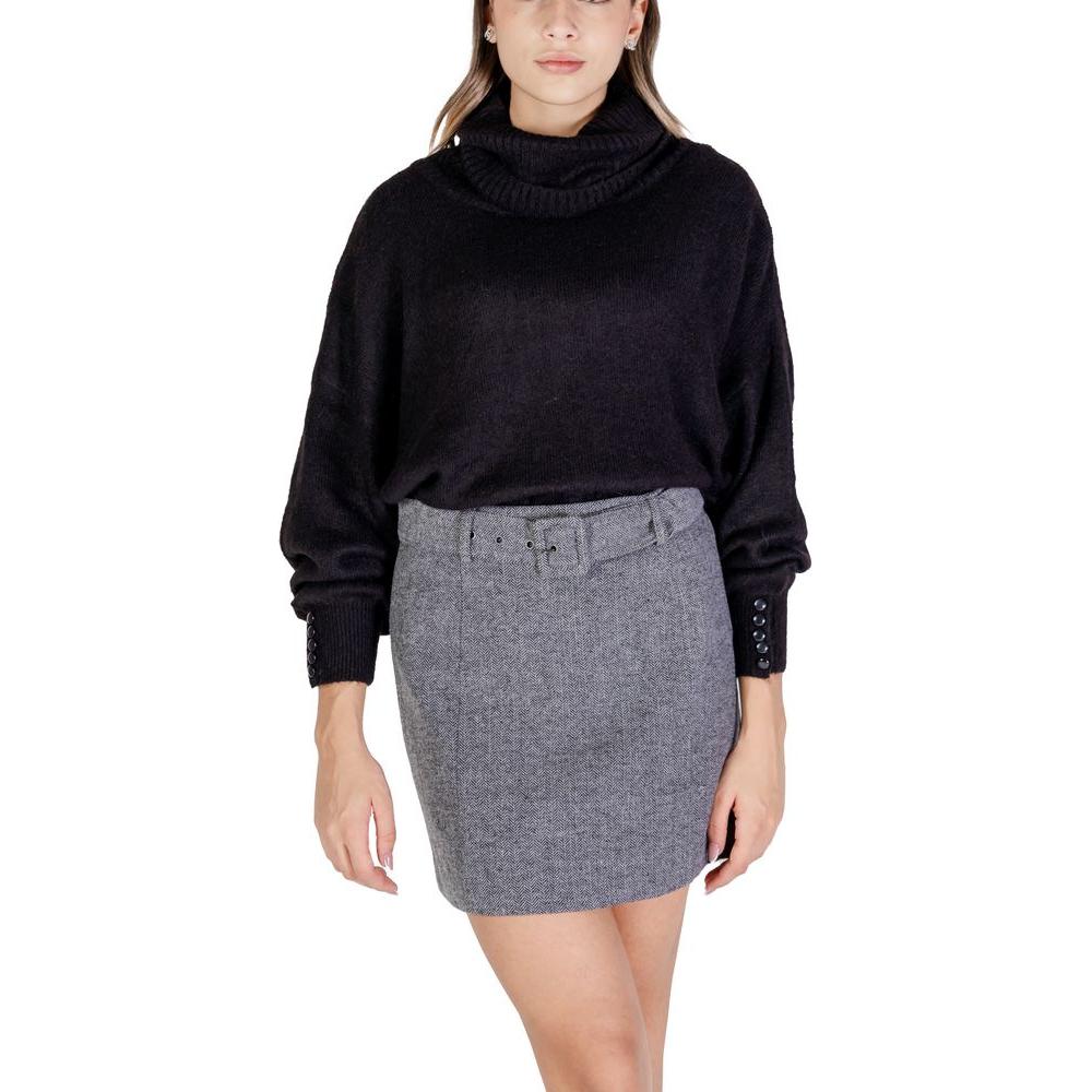 Woman wearing ICHI black acrylic sweater and gray skirt; women's knitwear, fall/winter collection, blend of acrylic and alpaca.