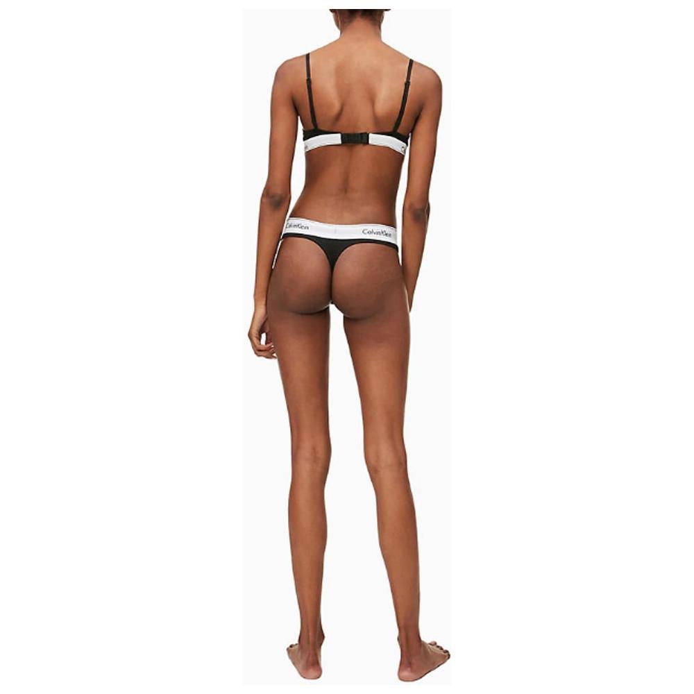 Back view of model wearing Calvin Klein black cotton thong underwear, showcasing minimalist design and comfort fit.