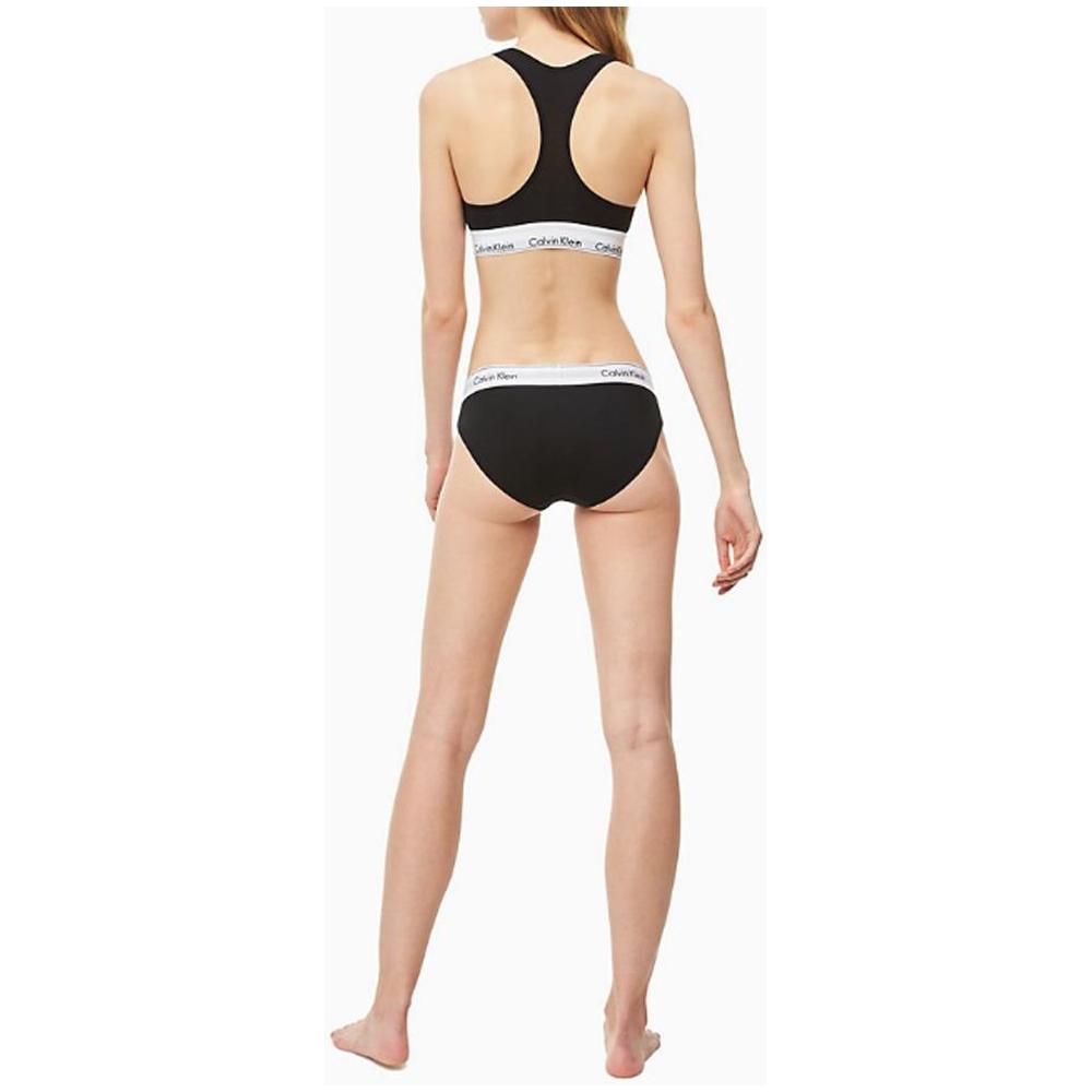 Back view of a woman wearing Calvin Klein black cotton underwear with logo waistband, showcasing comfort and minimalist style.
