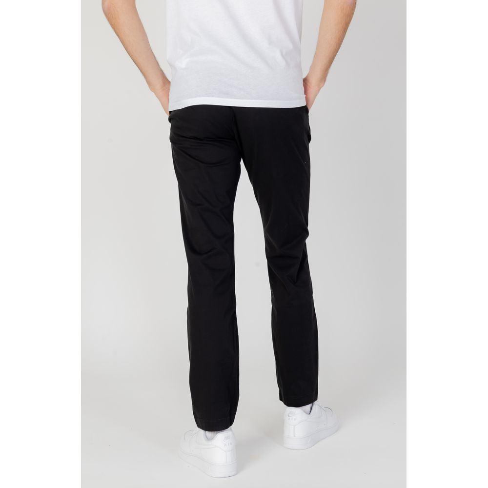 Back view of a person wearing Tommy Hilfiger black organic cotton tapered jeans from the Spring/Summer collection.