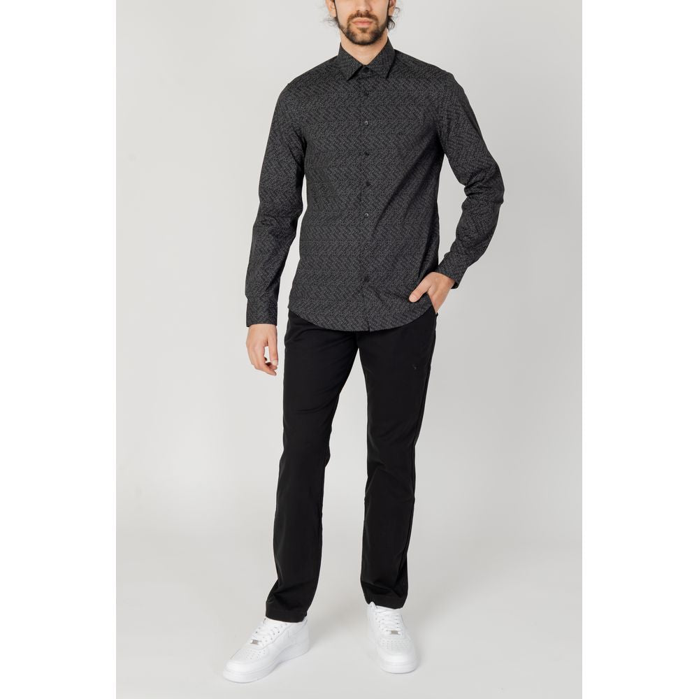 Man wearing Tommy Hilfiger black organic cotton jeans and shirt, showcasing a casual yet stylish look, perfect for spring/summer.