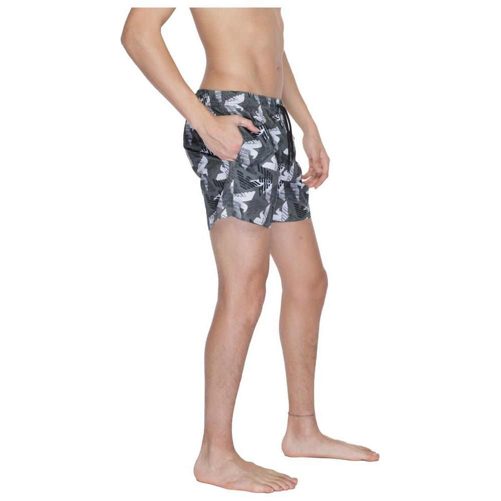 Emporio Armani black polyester swimwear boxer shorts with white bird print, worn by a model, featuring an elastic waistband.