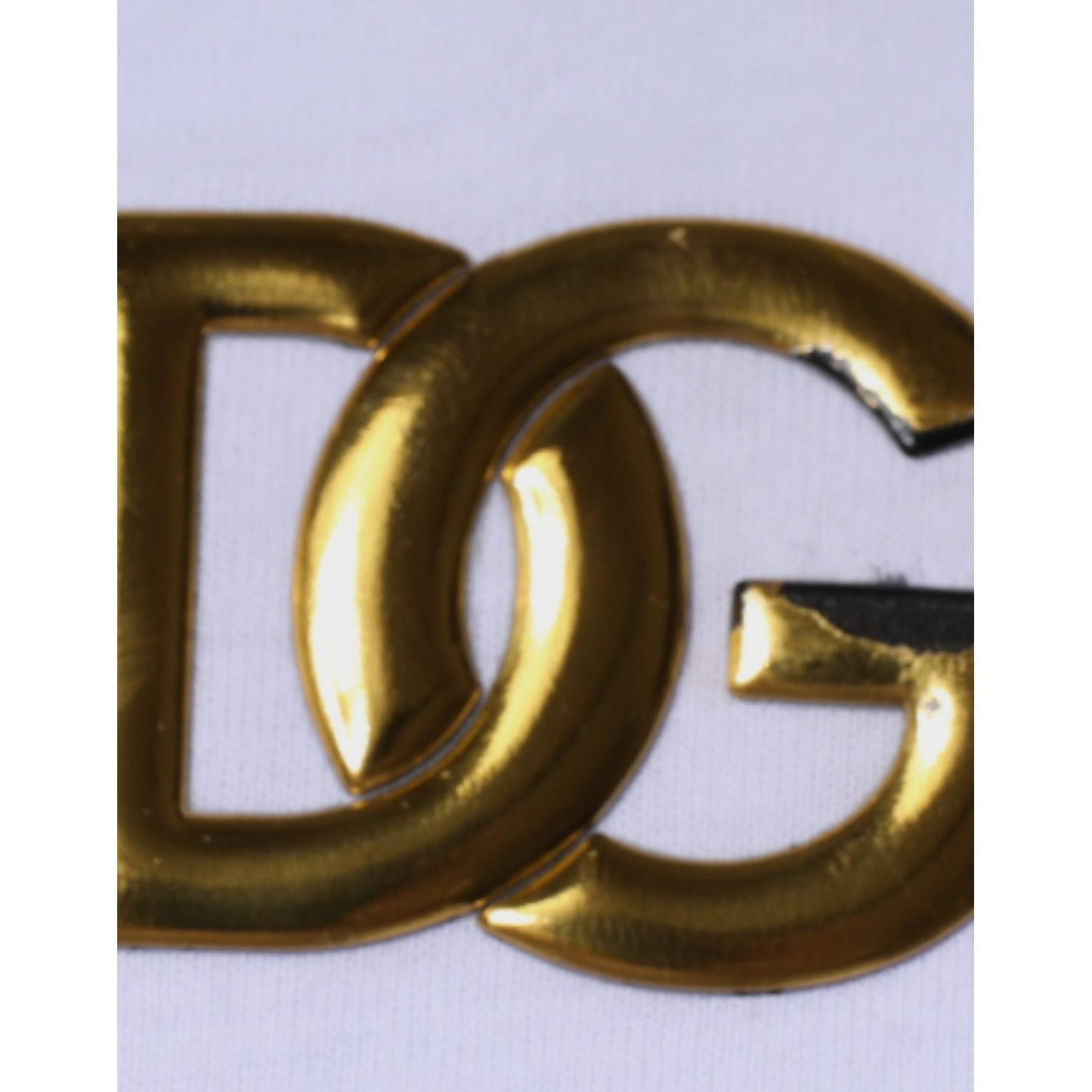 Gold metal DG logo on Dolce & Gabbana white V-neck cotton t-shirt showing minor defect with missing color on logo.