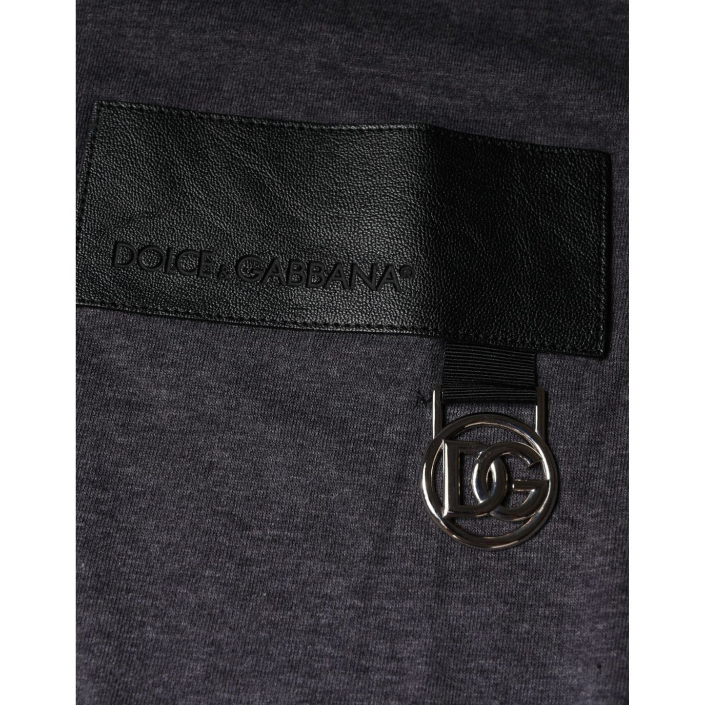 Dolce & Gabbana gray crew neck t-shirt close-up with leather logo patch and metal emblem detailing.