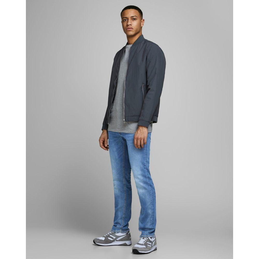 Man wearing Jack Jones blue slim fit jeans paired with grey jacket and sneakers, showcasing a casual yet stylish outfit.