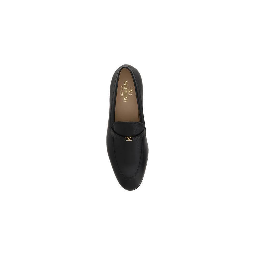 Valentino Garavani leather loafer with VLogo plaque, round toe, and slip-on design. Features a contrasting logo insole.