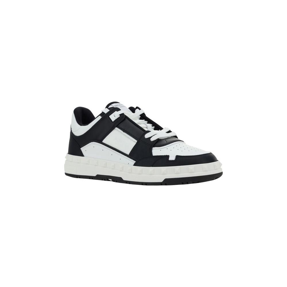 Valentino Garavani leather sneakers with laces, flat sole, conical heel studs, and embroidered logo on front tab.