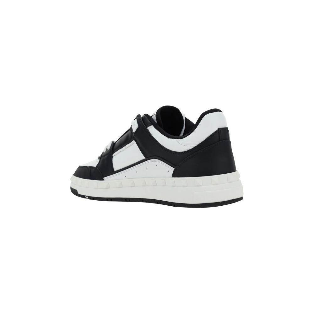 Valentino Garavani leather sneakers with conical heel studs and contrast stitching, featuring lace-up closure and flat sole.