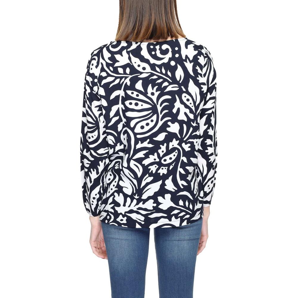 Back view of woman wearing a blue viscose long sleeve blouse with white floral pattern and denim jeans.