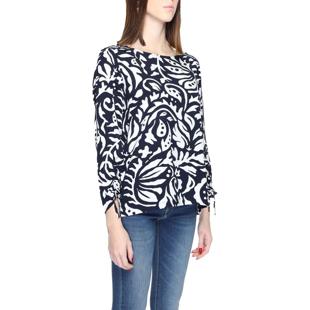 Woman wearing black and white patterned long sleeve viscose blouse, paired with jeans. Fashionable street-style casual wear.