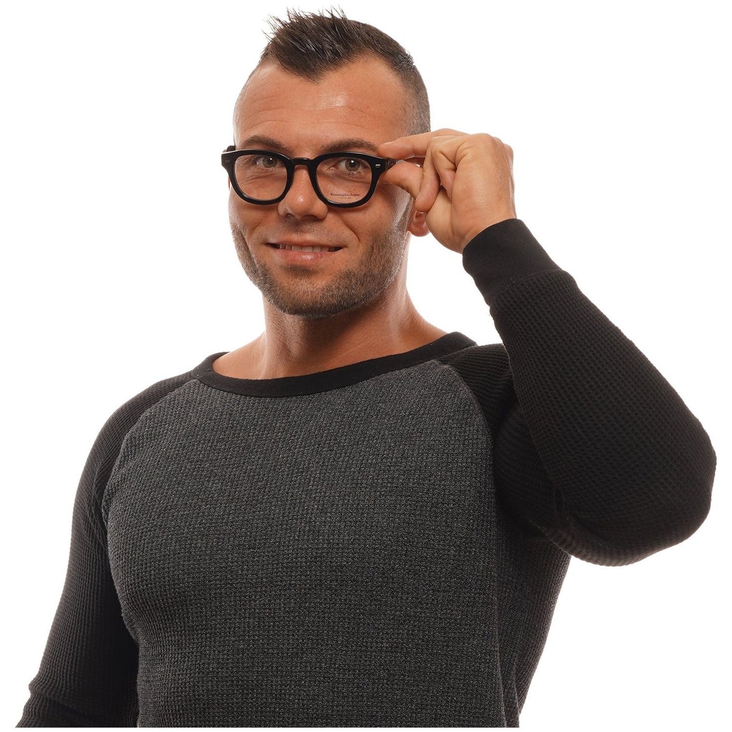 Man wearing black-rimmed glasses and a grey sweater, adjusting his eyewear with a confident expression, showcasing men's fashion eyewear.