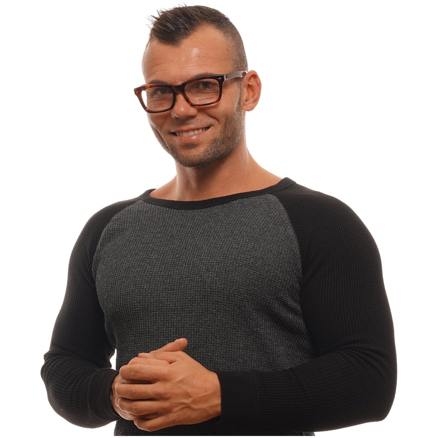 Man wearing black and gray sweater with brown rectangular glasses, smiling with arms folded.